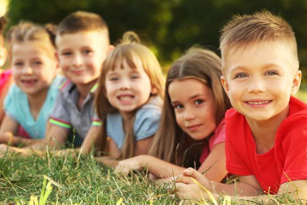 Bild mit Kindern, die im Gras liegen.